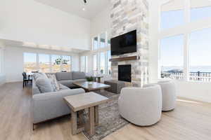 Living room with a stone fireplace, light wood-type flooring, and a high ceiling