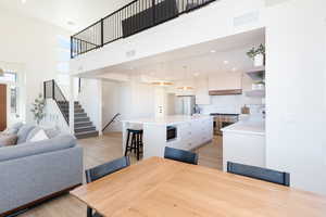 Dining area with light hardwood / wood-style flooring, a towering ceiling, and sink