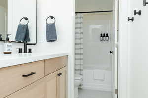 Full bathroom with shower / bath combination with curtain, vanity, and toilet