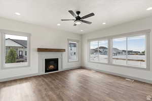 Unfurnished living room with ceiling fan, a textured ceiling, and hardwood / wood-style flooring