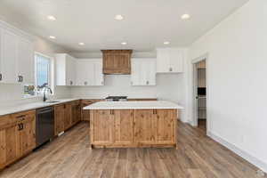 Kitchen with a center island, white cabinets, sink, light hardwood / wood-style floors, and stainless steel appliances