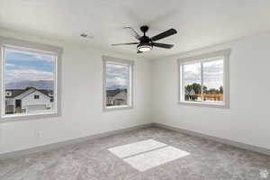 Unfurnished room featuring light carpet, ceiling fan, and a textured ceiling