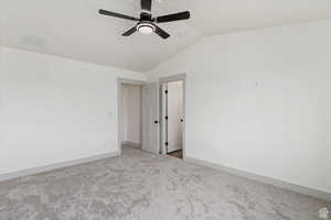 Carpeted spare room featuring ceiling fan and lofted ceiling