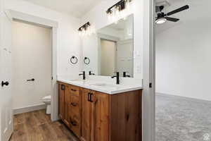 Bathroom with hardwood / wood-style floors, vanity, toilet, and ceiling fan