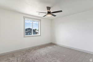 Carpeted spare room with ceiling fan and a textured ceiling