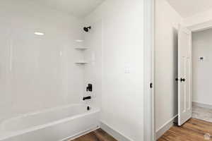 Bathroom with wood-type flooring and bathtub / shower combination