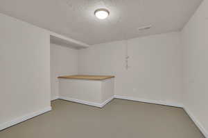 Empty room with a textured ceiling and concrete floors