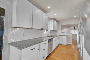 Kitchen with white cabinets, a healthy amount of sunlight, light wood-type flooring, and stainless steel appliances