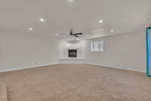 Unfurnished living room with ceiling fan and light colored carpet