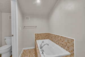 Bathroom with a relaxing tiled tub and toilet