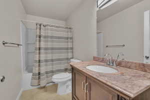 Full bathroom with shower / bath combo with shower curtain, tile patterned flooring, vanity, and toilet