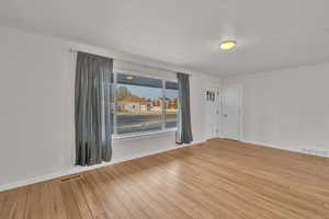 Spare room featuring a textured ceiling and light hardwood / wood-style floors