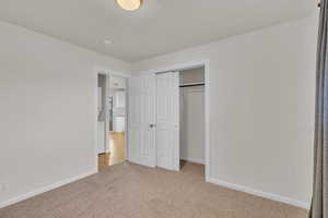 Unfurnished bedroom featuring a closet, light colored carpet, and a textured ceiling