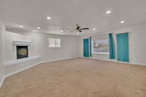 Unfurnished living room featuring ceiling fan and carpet floors