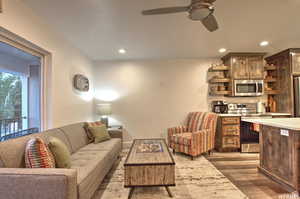 Living room with ceiling fan and dark wood-type flooring