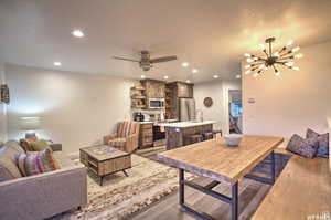 Living room with dark hardwood / wood-style flooring, ceiling fan with notable chandelier, and sink