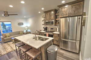 Kitchen with appliances with stainless steel finishes, dark hardwood / wood-style flooring, a center island with sink, and sink