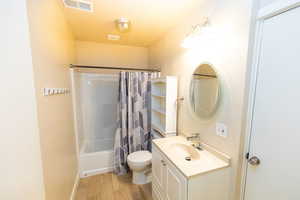 Full bathroom with shower / bath combo, toilet, wood-type flooring, and vanity