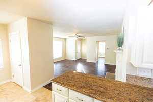 Kitchen with a textured ceiling, ceiling fan, dark stone countertops, white cabinets, and light hardwood / wood-style floors