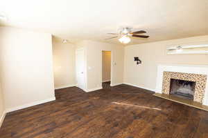 Unfurnished living room with a textured ceiling, ceiling fan, dark hardwood / wood-style flooring, and a fireplace