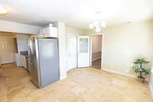 Kitchen featuring a chandelier, white cabinetry, decorative light fixtures, and stainless steel refrigerator with ice dispenser