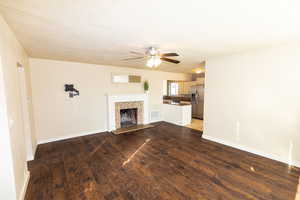 Unfurnished living room with hardwood / wood-style floors, ceiling fan, a textured ceiling, and a tiled fireplace