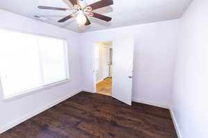 Unfurnished room with a textured ceiling, ceiling fan, and dark hardwood / wood-style floors