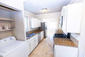 Kitchen featuring white cabinets, crown molding, sink, appliances with stainless steel finishes, and washer / dryer