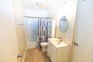 Full bathroom featuring shower / bath combo, toilet, wood-type flooring, and vanity