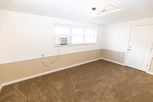 Carpeted spare room featuring cooling unit