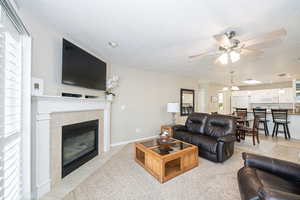 Tiled living room featuring ceiling fan, a textured ceiling, and a tile fireplace