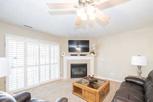 Living room with carpet flooring and a tiled fireplace, plantation shutter patio door