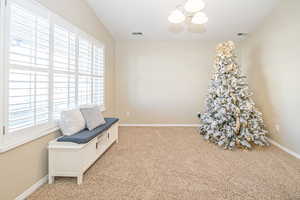 Sitting room with plenty of natural light, light colored carpet, and a chandelier