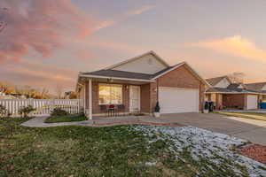 View of front facade featuring a lawn, a porch, and a garage