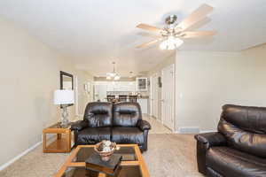 Living room with light carpet, a textured ceiling, and ceiling fan with notable chandelier