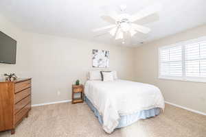 Primary Bedroom with ceiling fan and light colored carpet