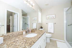 Primary Bathroom with tile patterned flooring, vanity, an enclosed shower, and toilet