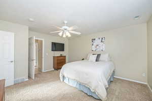 Primary Bedroom with light carpet, a textured ceiling, and ceiling fan