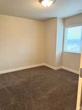 Spare room featuring dark colored carpet