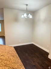 Unfurnished dining area featuring a chandelier and dark hardwood / wood-style floors