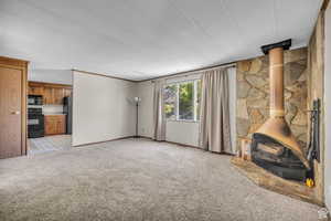 Unfurnished living room with a wood stove, light carpet, and a textured ceiling