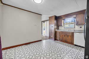 Kitchen with dishwasher, plenty of natural light, ornamental molding, and sink