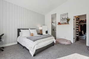 Bedroom featuring a walk in closet, carpet floors, a closet, and vaulted ceiling