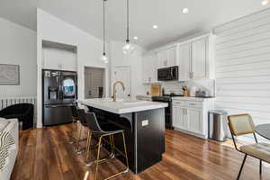 Kitchen with pendant lighting, refrigerator with ice dispenser, sink, an island with sink, and range with two ovens