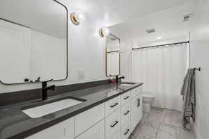 Bathroom featuring vanity, toilet, curtained shower, and a textured ceiling