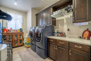 Washroom featuring cabinets, light hardwood / wood-style floors, and washing machine and dryer