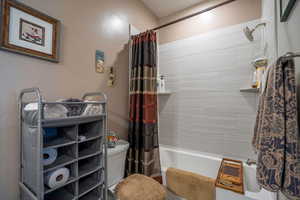 Bathroom with toilet and shower / tub combo with curtain