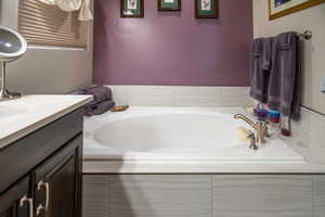 Bathroom featuring vanity and tiled bath