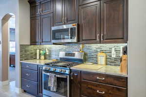 Kitchen featuring dark brown cabinets, stainless steel appliances, and light hardwood / wood-style flooring