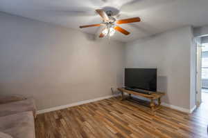 Unfurnished living room with dark hardwood / wood-style flooring and ceiling fan